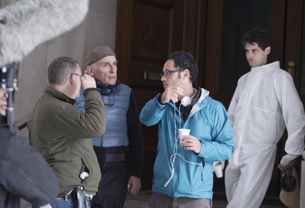 Omer Fast (centre, in blue) talks with the team of Remainder on set. Courtesy of Soda Pictures.