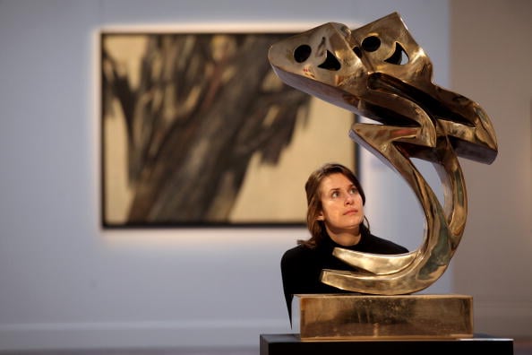 A gallery assistant at Sotheby’s London views a sculpture by Parviz Tanavoli entitled Standing Heech Lovers, ahead of the Contemporary Arab and Iranian art sale on October 18, 2010. Photo by Oli Scarff/Getty Images.