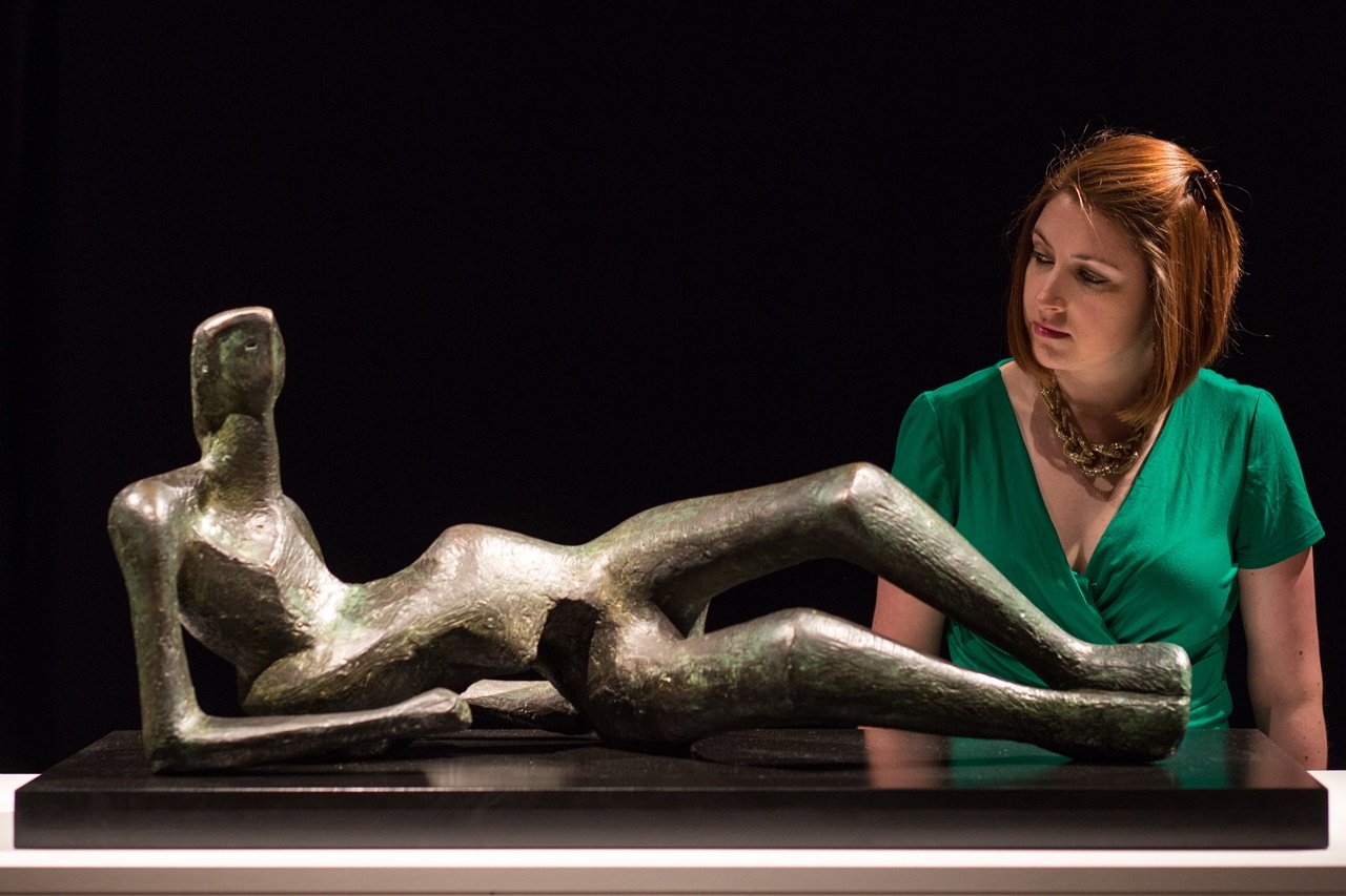 A Christie’s staffer with Henry Moore's sculpture Reclining Figure No. 2 (conceived in 1952) at Christie's King Street, London, in 2015. Photo by Rob Stothard/Getty Images.