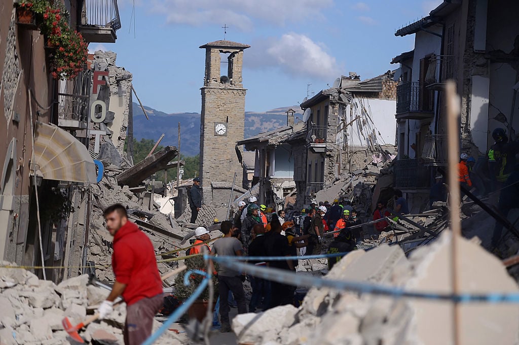 Rescuers and firemen inspect the rubble of buildings in Amatrice on August 24, 2016 after a powerful earthquake rocked central Italy. Scores of buildings were reduced to dusty piles of masonry in communities close to the epicentre of the pre-dawn quake in a remote area straddling the regions of Umbria, Marche and Lazio. Photo Filipo Monteforte/AFP/Getty Images.