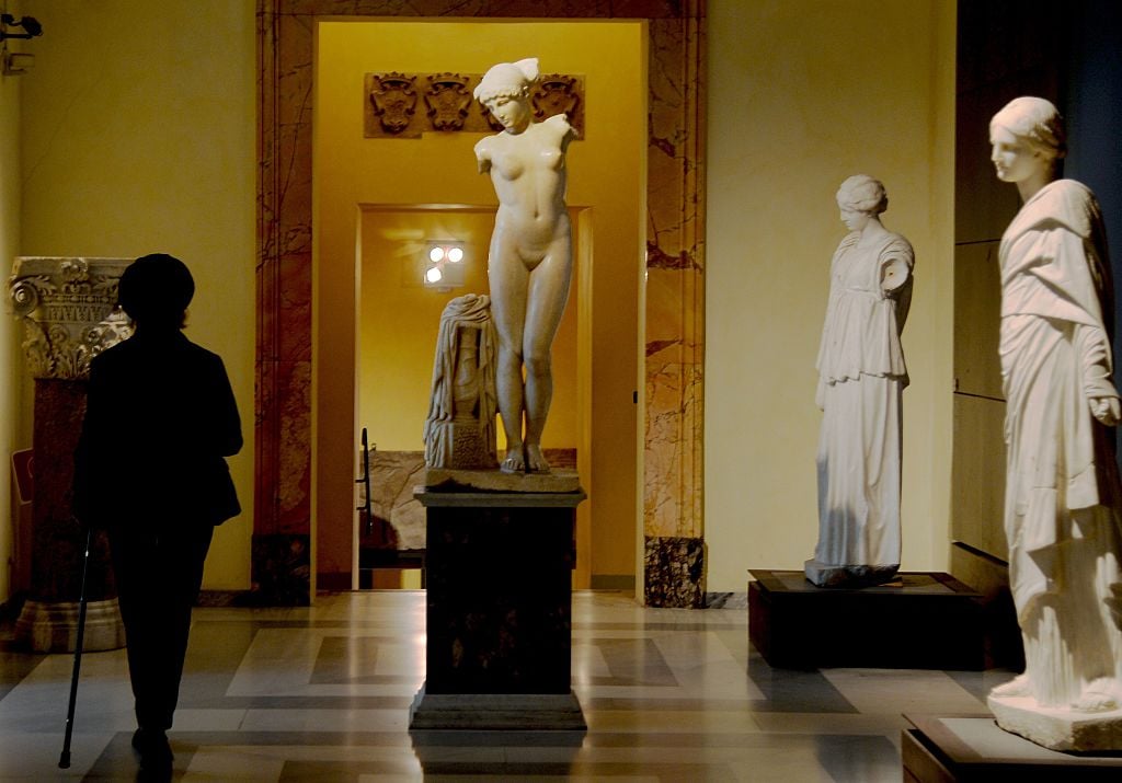 A picture taken on January 26, 2016 shows a visitor walking past an ancient Roman marble statue at Rome's Capitoline Museum (Musei Capitolini) on Capitol Hill. Courtesy of FILIPPO MONTEFORTE/AFP/Getty Images.