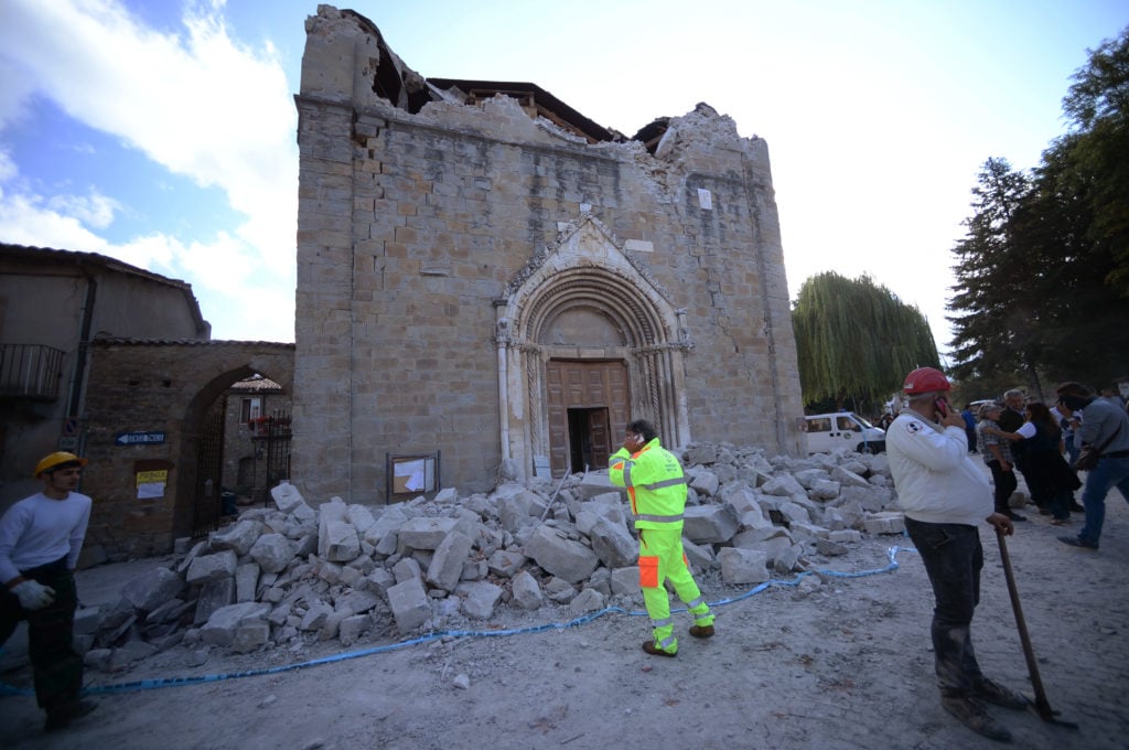 People stand in front of a damaged church in Amatrice on August 24, 2016. Photo: Filippo Monteforte/AFP/Getty Images.