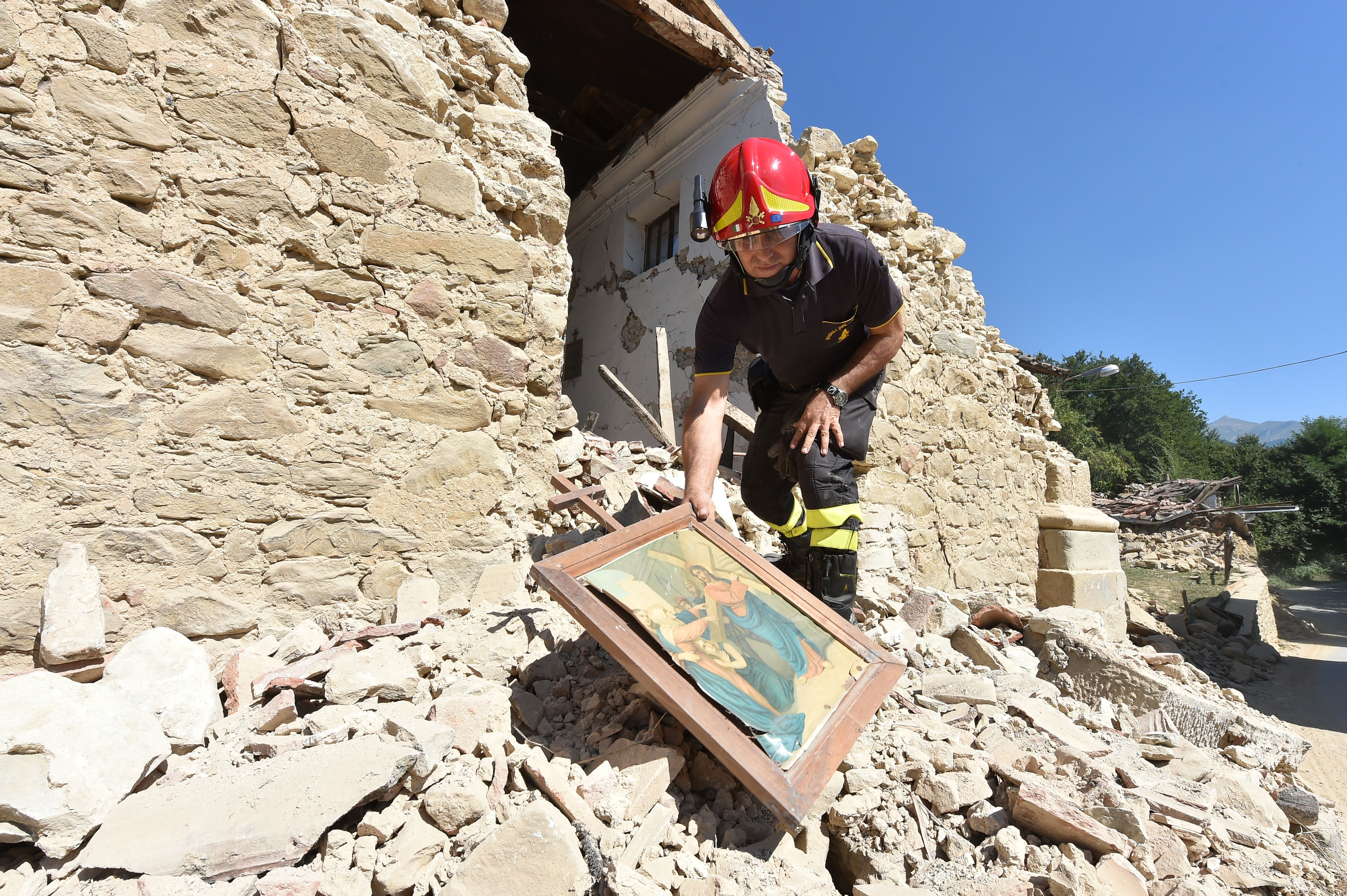 Firefighters recover a religious painting from a damaged church in the village of Rio, some 10 kms from the central Italian village of Amatrice, on August 28, 2016. Photo: ALBERTO PIZZOLI/AFP/Getty Images.