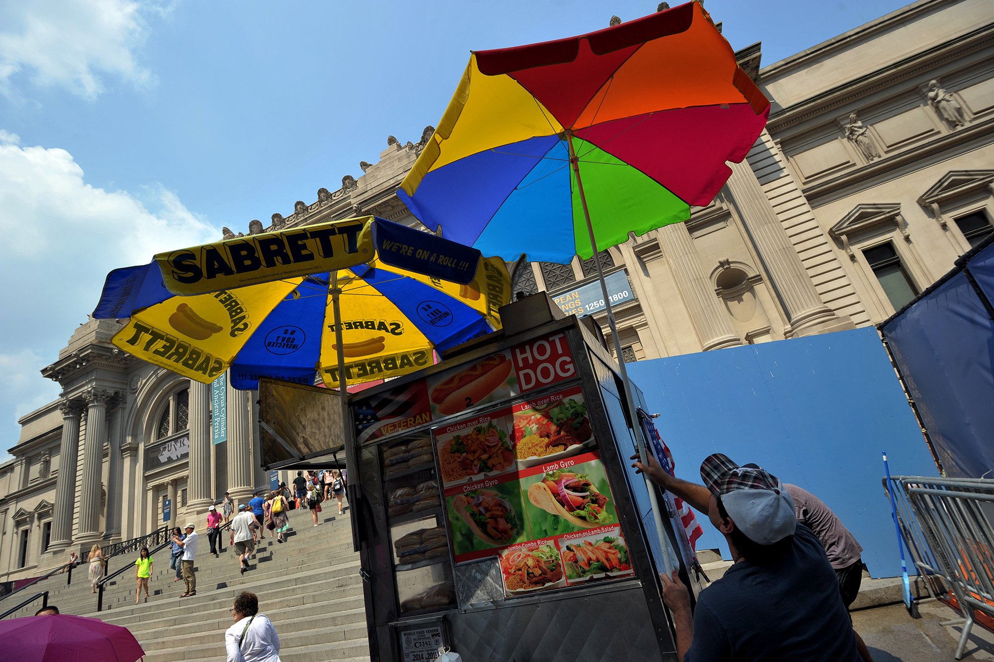 A hot dog vendor puts up another umbrella in front of the Metropolitan Museum of Art in New York. Courtesy of Stan Honda/AFP/Getty Images.