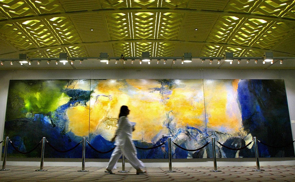 A woman walks past the world's largest triptych ever, produced by painter Zao Wou-ki, in Hong Kong, 26 May 2005. Courtesy of PHILIPPE LOPEZ/AFP/Getty Images.