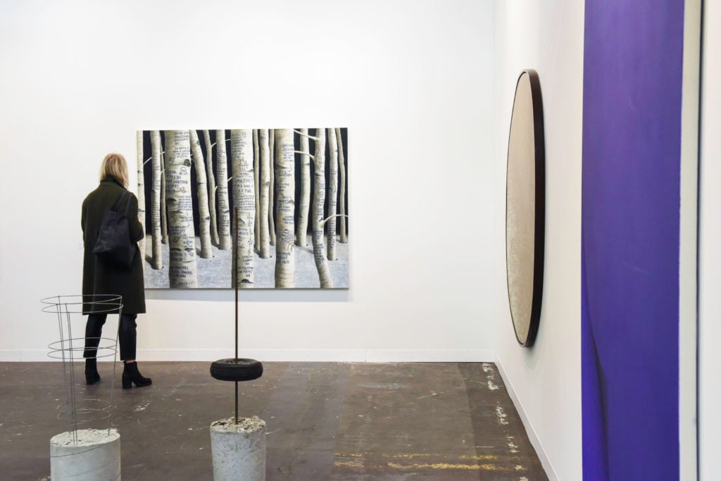 A visitor checks out a painting by Sean Landers at Galerie Rodolphe Janssen on Pier 94 at the Armory Show 2016. Photo BFA, courtesy the Armory Show 2016.