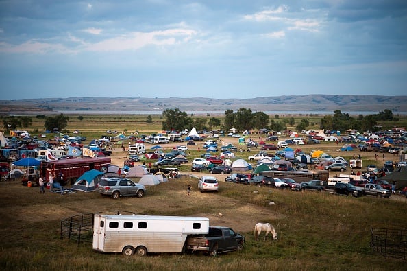 People gather at an encampment by the Missouri River, where hundreds of people have gathered to join the Standing Rock Sioux Tribe's protest against the construction of the Dakota Access Pipe (DAPL), near Cannon Ball, North Dakota, on September 3, 2016. The Indian reservation in North Dakota is the site of the largest gathering of Native Americans in more than 100 years. Indigenous people from across the US are living in camps on the Standing Rock reservation as they protest the construction of the new oil pipeline which they fear will destroy their water supply. / AFP / Robyn BECK (Photo credit should read ROBYN BECK/AFP/Getty Images)