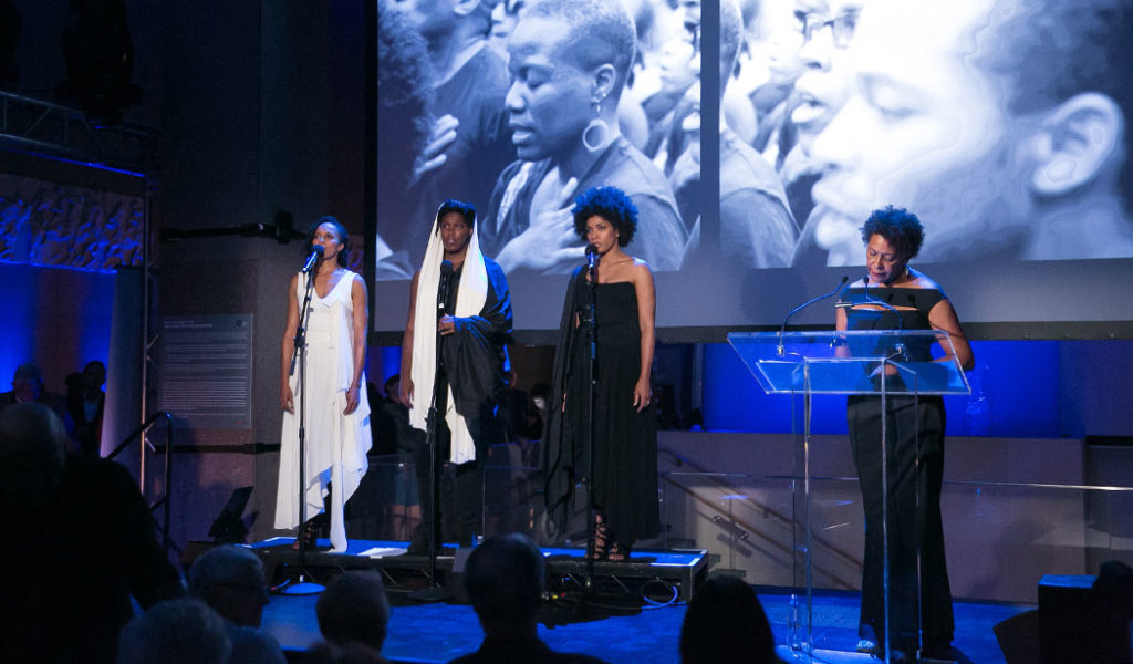 Carrie Mae Weems performing <em>Past Tense</em> with performers (from left to right) Eisa Davis, Imani Uzuri, and Alicia Hall Moran, at the Onassis Festival NY 2016, Antigone Now, Onasiss Cultural Center. Courtesy of Beowulf Sheehan.