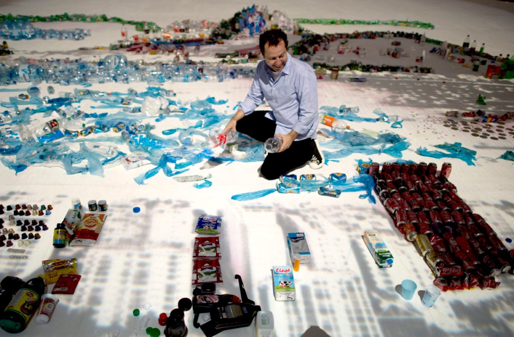 Brazilian artist Vik Muniz is seen with his work made of trash, portraying the sugar loaf in Rio de Janeiro. Courtesy Getty Images.