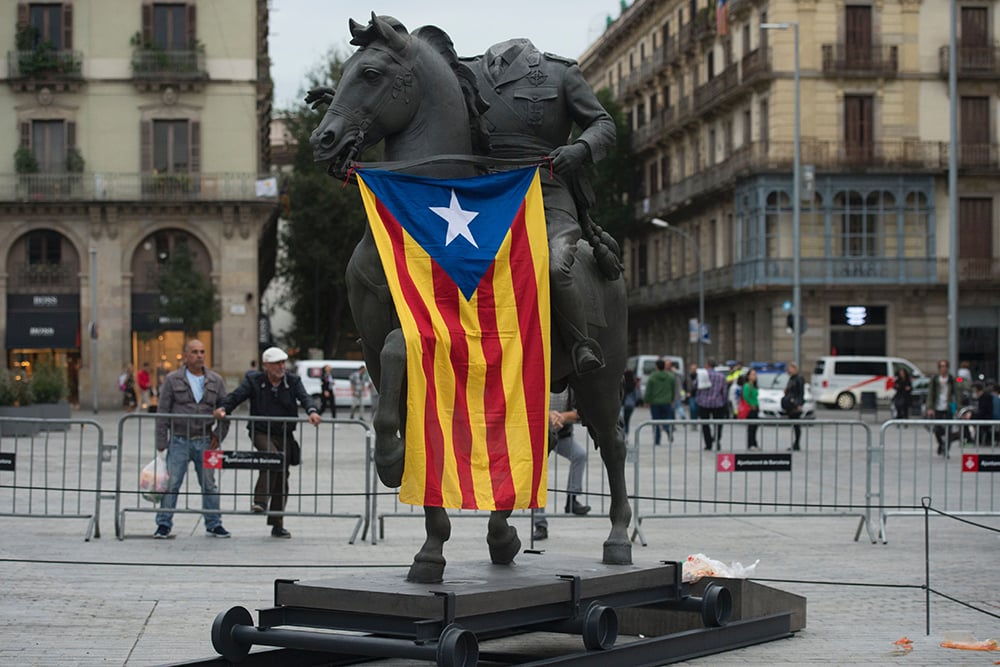 An Estelada, a Catalan Pro-independence flag, hangs from a headless sculpture of the late Spanish dictator Francisco Franco riding a horse, during the installation of a temporary exhibit titled "Franco, Victory, Republic, Impunity and Urban Space." Courtesy of Josep Lego/AFP/Getty Images.
