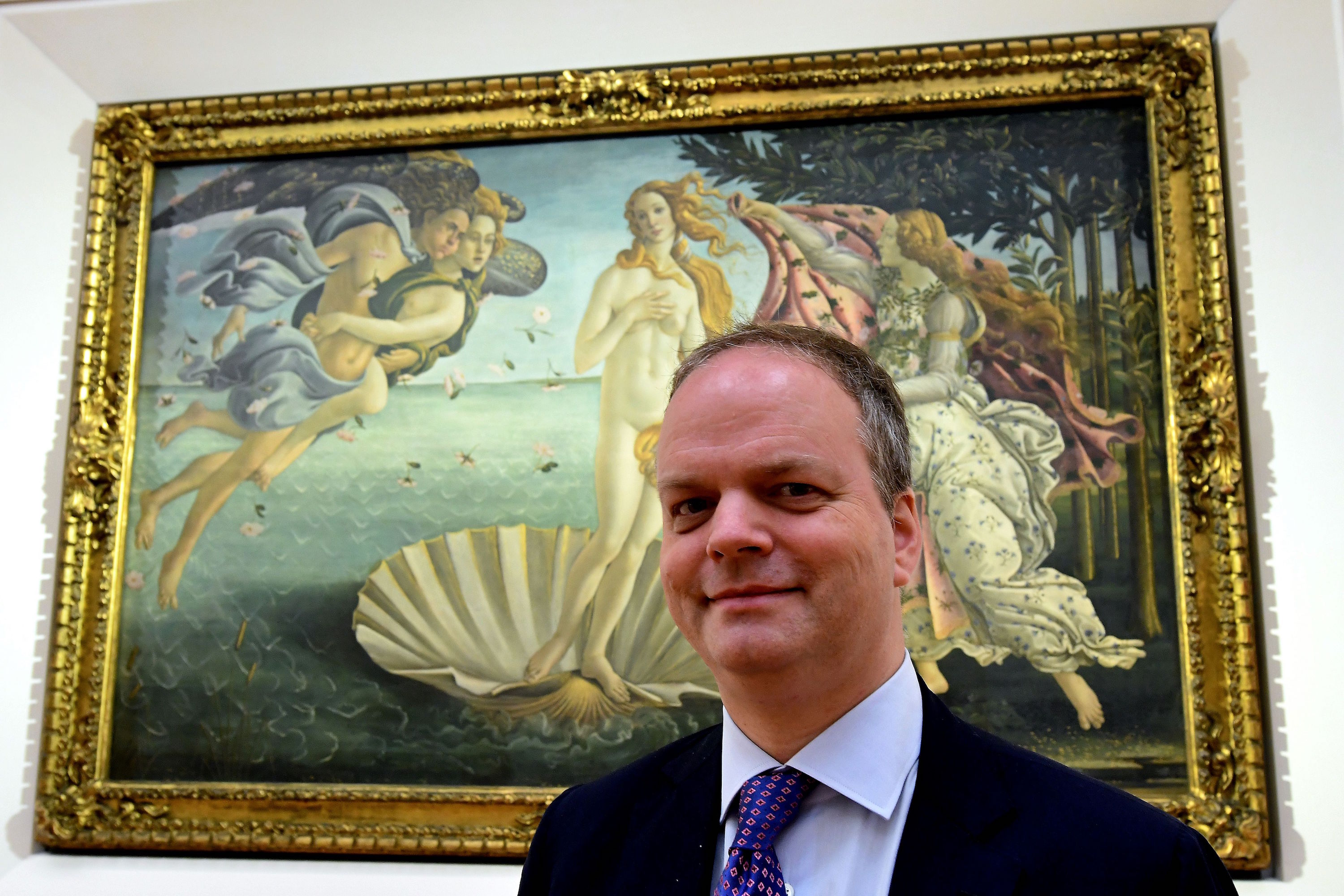 Eike Schmidt, director of Uffzi Gallery, poses in front of The birth of Venus (circa mid 1480s) by Sandro Botticelli during a press preview for the reopening of the rooms dedicated to Pollaiolo and Botticelli, at the Uffizi Gallery in Florence, on October 17, 2016. Photo Alberto Pizzoli/AFP/Getty Images.