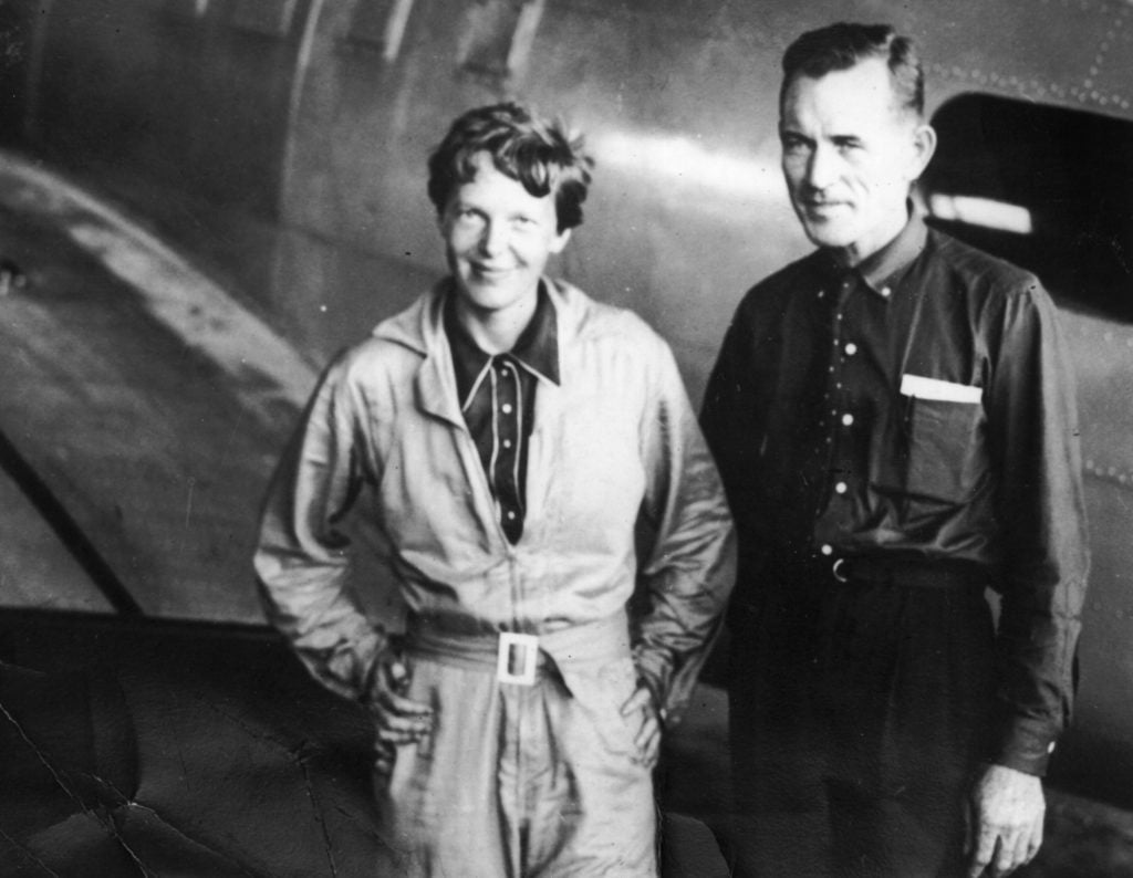 American aviatrix Amelia Earhart with her navigator, Fred Noonan, in the hangar at Parnamerim airfield, Natal, Brazil, June 11, 1937, shortly before their disappearance during their attempted circumnavigation of the globe. Courtesy of Topical Press Agency/Getty Images.