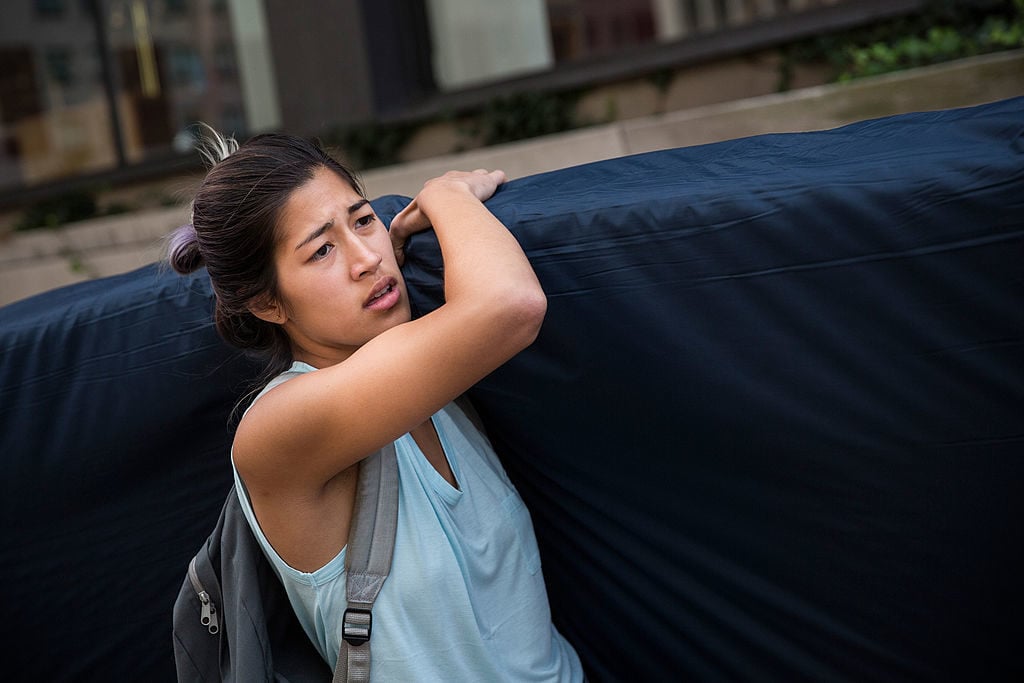 Emma Sulkowicz carries a mattress in protest of the university's lack of action after she reported being raped during her sophomore year. Photo by Andrew Burton, courtesy Getty Images.