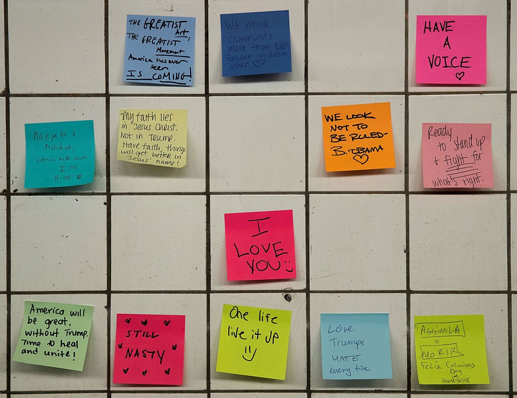 Post-it notes, many with politically themed messages, hang on a wall at the 6th Avenue subway station as part of a public art project entitled Subway Therapy. November 10, 2016 in New York City. Artist Matthew Chavez, who goes by 'Levee,' created the 'Subway Therapy' wall to offer New Yorkers a chance to write down their feelings in the wake of the presidential election. Photo Drew Angerer/Getty Images.