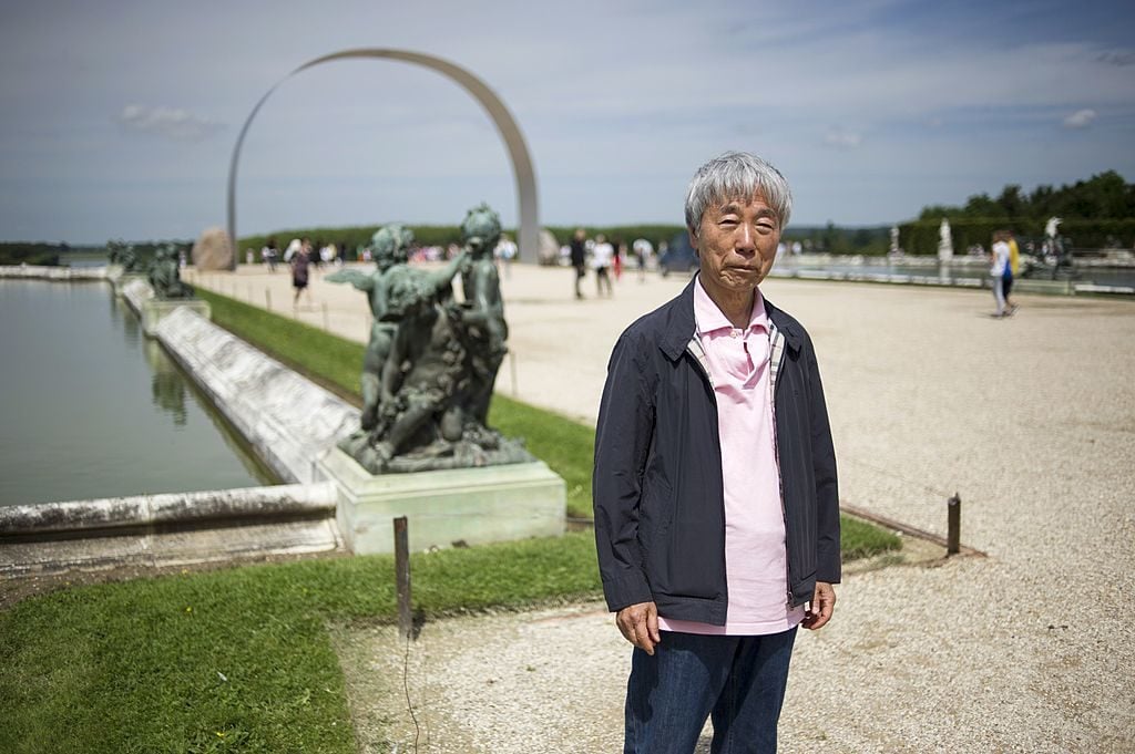 Lee Ufan poses near one of his artworks entitled "L'arche de Versailles" ('The arch of Versailles'), on June 11, 2014. at the Chateau de Versailles, during the exhibition "Lee Ufan Versailles". Painter and sculptor Lee Ufan, 77, has created a variety of artworks made of stone and steel for an exhibition at the Chateau de Versailles, outside Paris. Photo courtesy Fred Dufour/AFP/Getty Images.