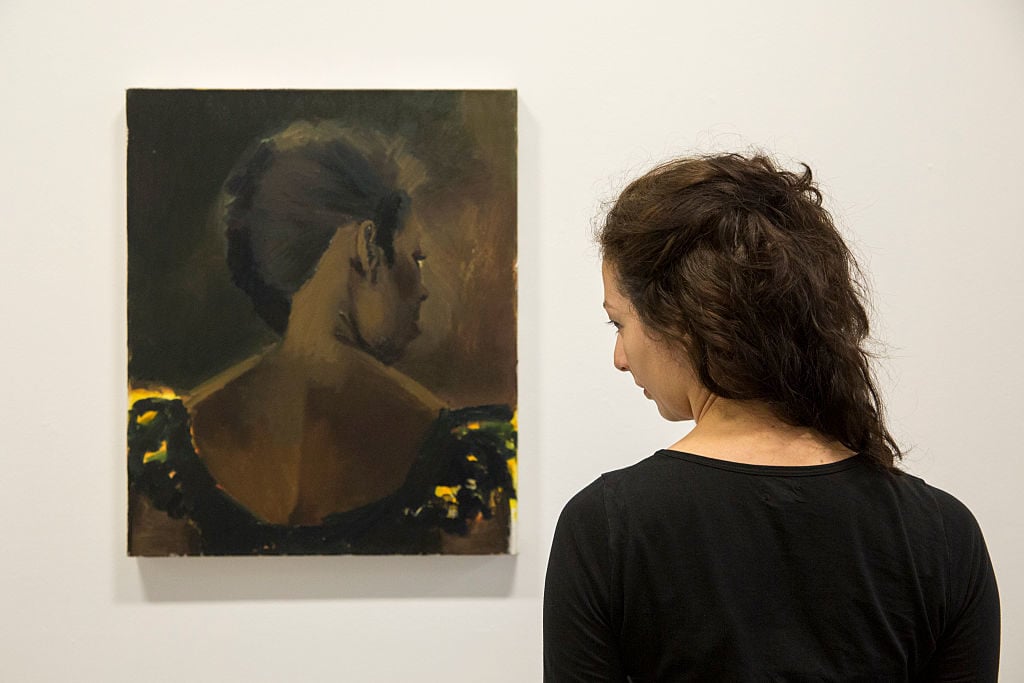 A member of the gallery staff poses beside Lynette Yiadom-Boakye's 2015 painting 'The Matches' at the Serpentine Gallery on June 1, 2015. Photo by Rob Stothard/Getty Images.