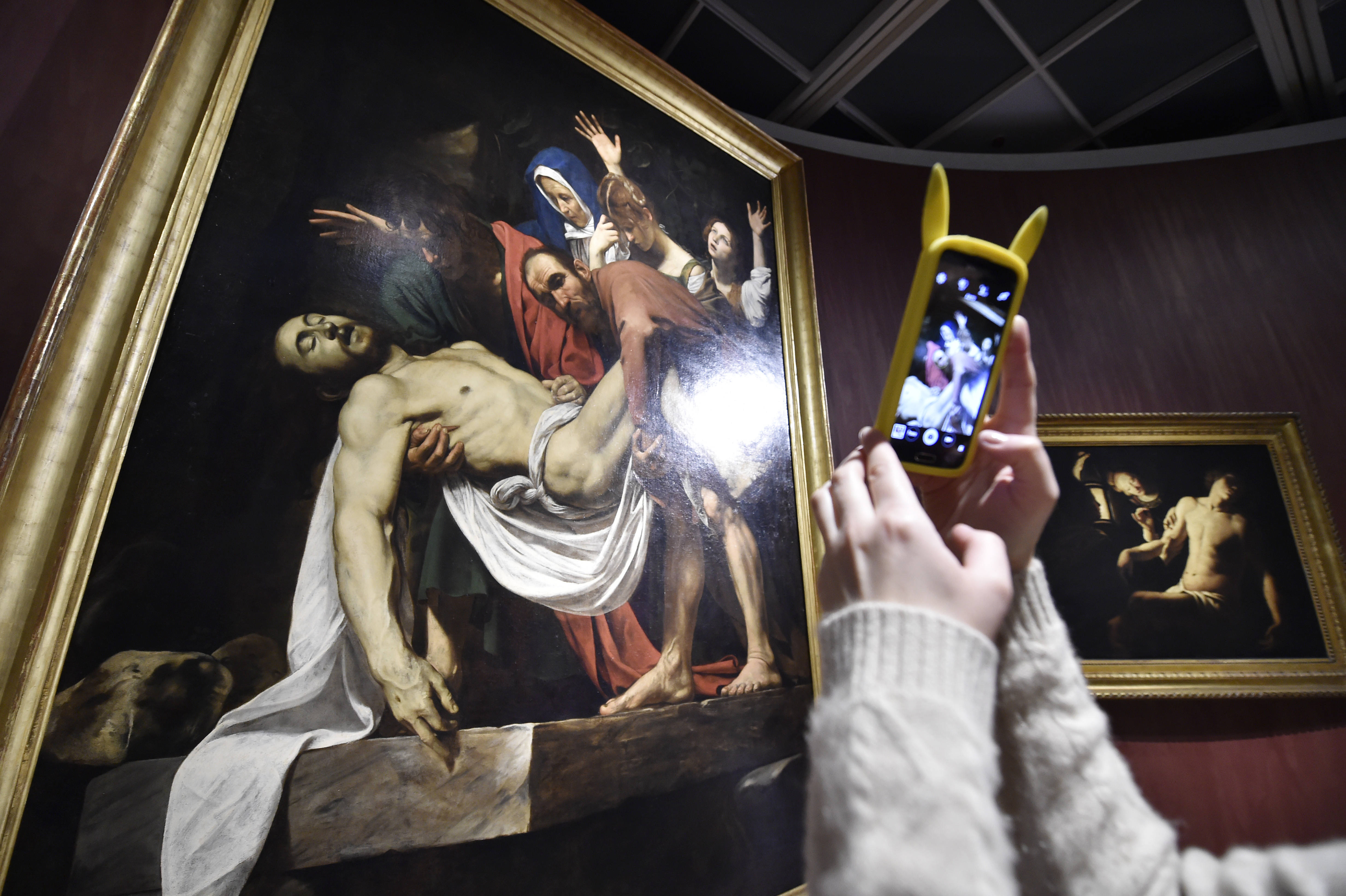 A woman takes pictures with a mobile phone of "The Deposition" (1603-1604) by Michelangelo Merisi known as The Caravaggio during a press preview of the exhibition entitled "Roma Aeterna. Masterpieces of the Vatican Pinacotheca. Bellini, Raphael, Caravaggio" at the Tretyakov Gallery in Moscow on November 23, 2016. The exhibition, which focuses on the works of XII to XVIII centuries, including the paintings by Raphael, Caravaggio, Bellini, Guercino, Perugino, Poussin, Reni, from the Vatican Museums, opens November 25 and runs through February 19, 2017. / AFP / Natalia KOLESNIKOVA / RESTRICTED TO EDITORIAL USE - MANDATORY MENTION OF THE ARTIST UPON PUBLICATION - TO ILLUSTRATE THE EVENT AS SPECIFIED IN THE CAPTION (Photo credit should read NATALIA KOLESNIKOVA/AFP/Getty Images)