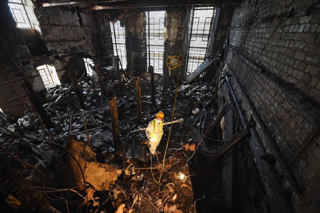 Forensic archaeologist Owen Godbert sifts through the ashes of the fire damaged Mackintosh Library at the Glasgow School of Art on November 18, 2014 in Glasgow, Scotland. Photo Courtesy Jeff J Mitchell/Getty Images.