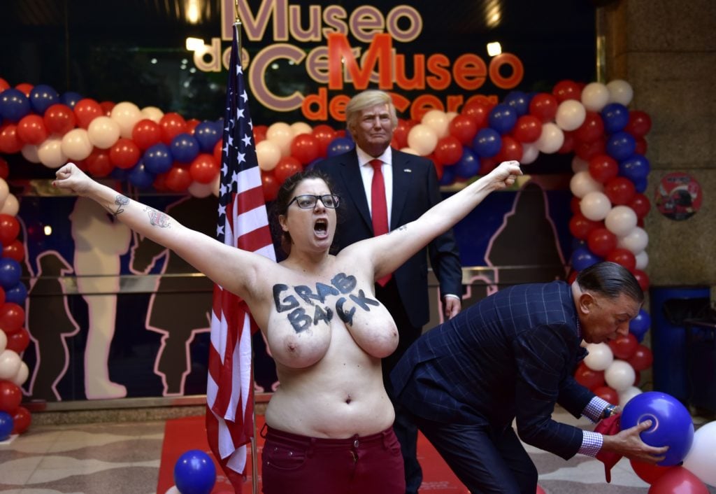 Madrid Wax Museum director Gonzalo Presa tries to stop a topless Femen activist as she protests in front of a wax statue of US President-elect Donald Trump during its unveiling. Courtesy of Gerard Julien/AFP/Getty Images.