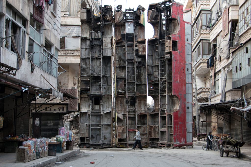 A young boy walks past a makeshift barricade made of wreckages of buses to obstruct the view of regime snipers and to keep people safe, on March 14, 2015 in the rebel-held side of the northern Syrian city of Aleppo. Syria's conflict enters its fifth year on March 15, 2015 with the regime emboldened by shifting international attention and a growing humanitarian crisis exacerbated by the rise of the Islamic State group. AFP PHOTO / KARAM AL-MASRI / AFP / KARAM AL-MASRI AND - (Photo credit should read KARAM AL-MASRI/AFP/Getty Images)