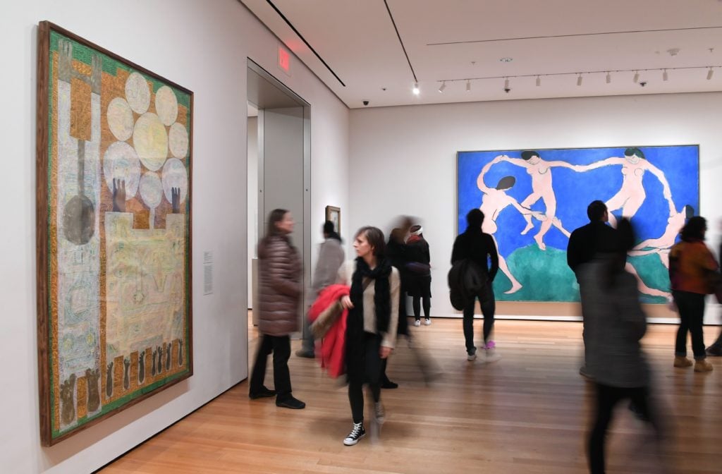 Visitors look at artwork by Iranian painter and sculptor Charles Hossein Zenderoudi at the Museum of Modern Art on February 3, 2017 in New York City. The famed New York art museum has joined the throng of protests against US President Donald Trump's travel ban by replacing Western art with pieces by Iranian, Iraqi and Sudanese-born artists. Courtesy of Angela Weiss/AFP/Getty Images.
