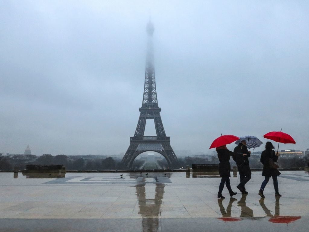 People with umbrellas walk on the human rights plaza in front of the Eiffel tower during a rainy morning in Paris on February 7, 2017. Photo Ludovic Marin/AFP/Getty Images.