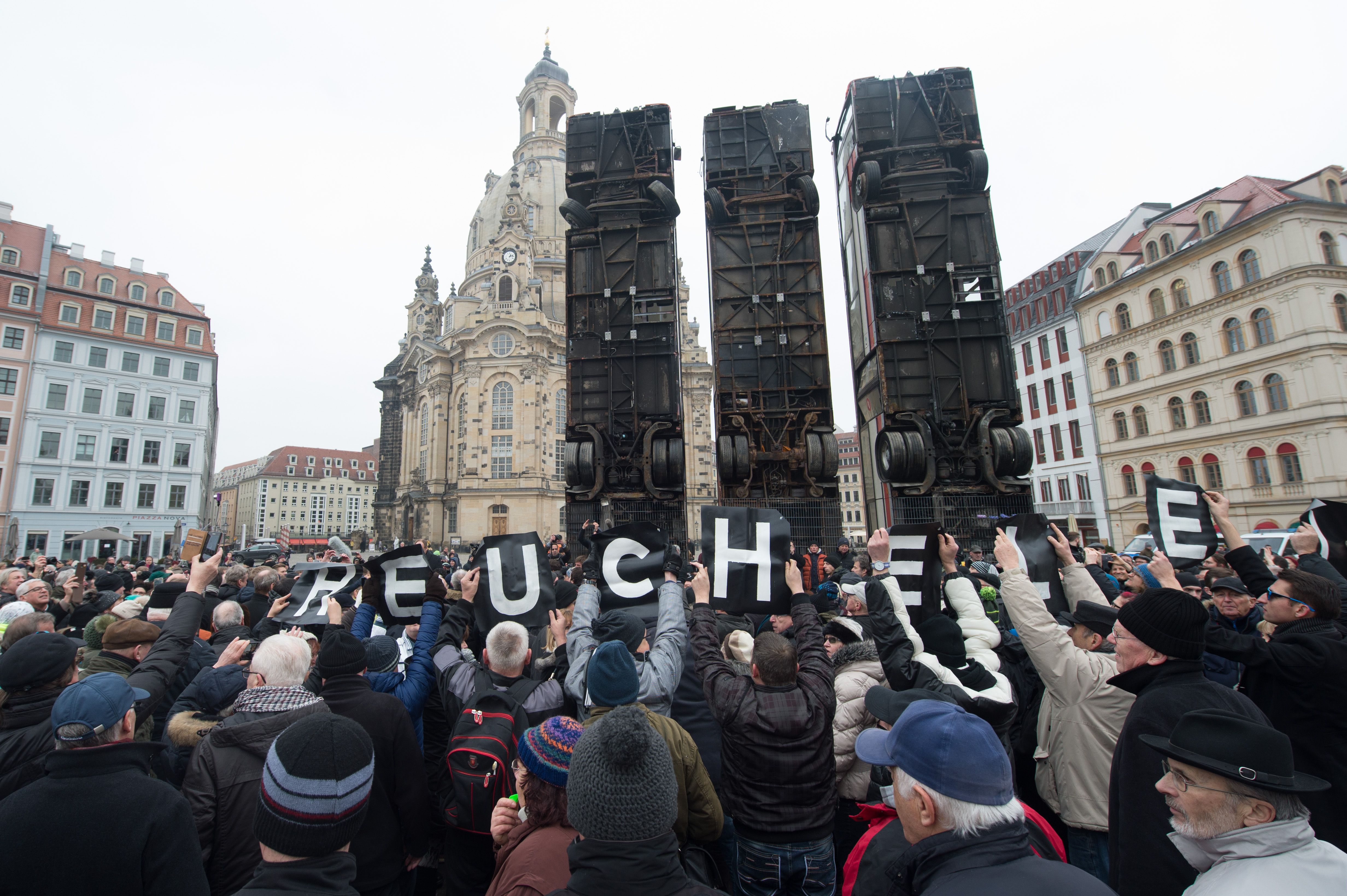 Demonstrators hold up posters reading "hypocrisy" as they protest against an installation made of buses titled Monument by Syrian-born artist Manaf Halbouni erected at the Neumarkt square in Dresden, eastern Germany, on February 7, 2017. The artwork, that aims to evoke the barricades set up in the war-torn eastern city of Aleppo and the suffering of the people of Syria, has drawn fierce criticism from far-right groups. Courtesy of Sebastian Kahnert/AFP/Getty Images.