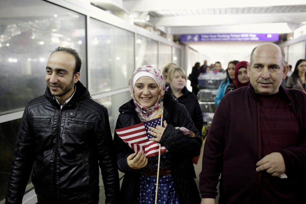 Syrian refugee Baraa Haj Khalaf, (C), holds the American flag as she walks with her husband Abdulmajeed (L) and father Khaled Haj Khalaf as she leaves O'Hare International Airport on February 7, 2017 in Chicago, Illinois. Baraa Haj Khalaf and her family were previously barred from entering the United States after President Donald Trump signed an executive order temporarily banning refugees. The Justice Department faced tough questioning as it urged a court of appeals to reinstate President Donald Trump's travel ban targeting citizens of seven Muslim-majority countries, put on hold by the courts last week. Courtesy of Joshua Lott/AFP/Getty Images.