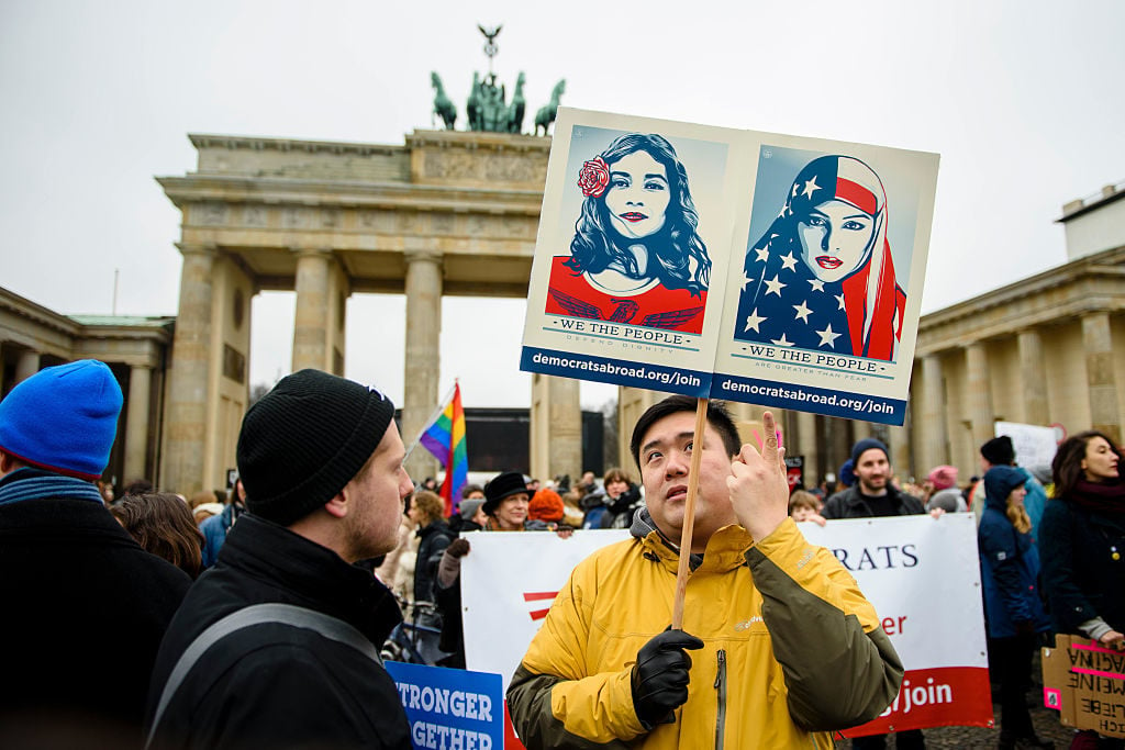 A demonstrator holds up a poster from the "We the People" campaign of US artist Shepard Fairey. Photo: GREGOR FISCHER/AFP/Getty Images.