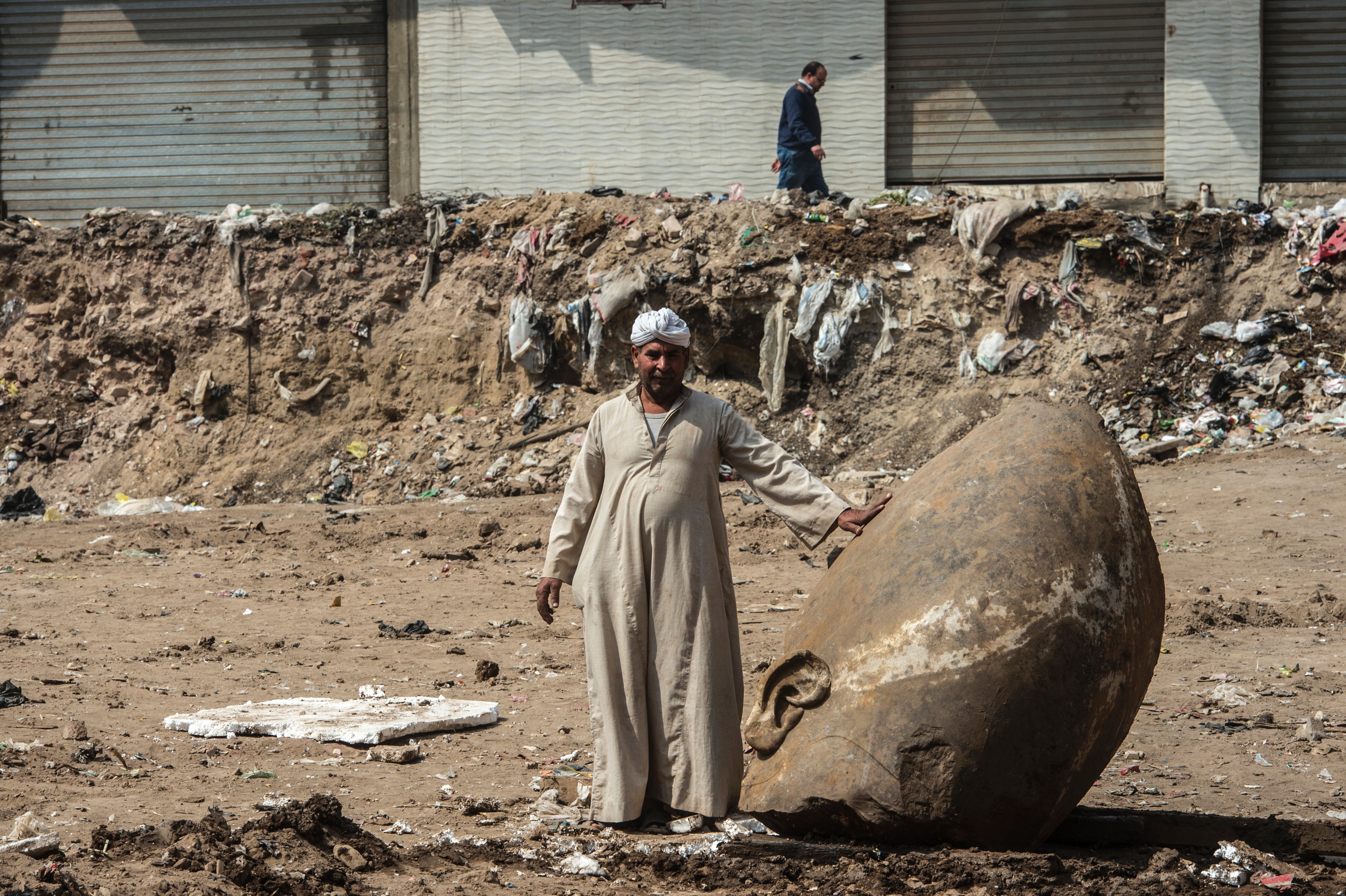 An Egyptian worker stands next to the head of statue at the site of a new discovery by a team of German-Egyptian archeologists in Cairo's Mattarya district on March 9, 2017. Courtesy of Khaled Desouki/AFP/Getty Images.