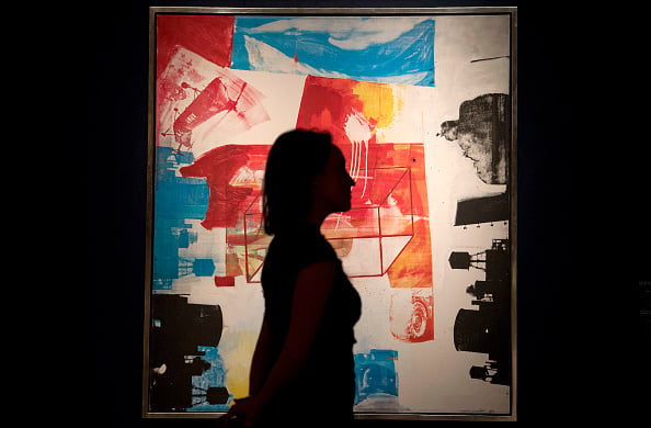 An employee poses with an artwork by American painter Robert Rauschenberg entitled Transom, during a photocall ahead of the Post-War and Contemporary art sale at Christie's London on March 3, 2017. Photo credit should read JUSTIN TALLIS/AFP/Getty Images.
