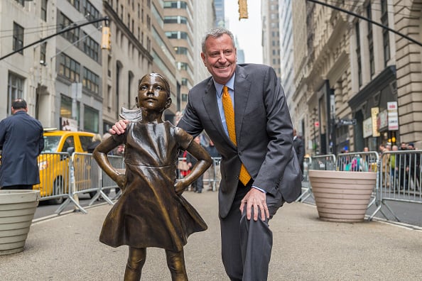 Mayor De Blasio poses with the "Fearless Girl" sculpture. NYC Mayor De Blasio held a photo-op and a press conference to announce that the "Fearless Girl" sculpture installed on International Women's Day 2017 at the triangular intersection of Broadway and Whitehall Street in New York will remain in place through International Women's Day in 2018. Photo by Albin Lohr-Jones/Pacific Press/LightRocket via Getty Images.