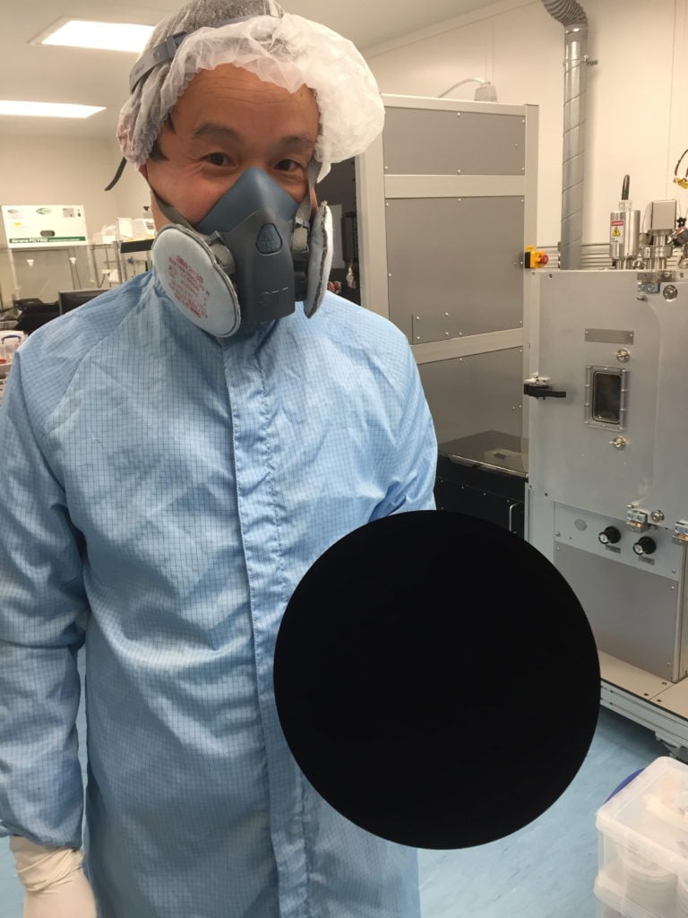 A Surrey NanoSystems technician demonstrating a three-dimensional bowl-shaped object spray-coated with Vantablack. Image courtesy Surrey NanoSystems.