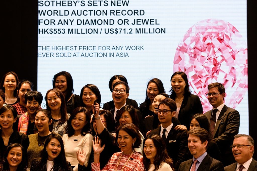 Sotheby's staff gather for a group photo following the sale of a 59.60-carat giant diamond named the "Pink Star", breaking the world record for a gemstone sold at auction, fetching $71.2 million. Courtesy of Anthony Wallace/AFP/Getty Images.