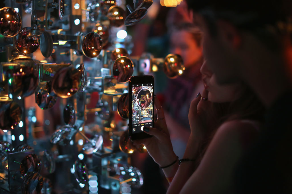 Festivalgoers interact with the installation "Lamp Beside the Golden Door." Photo by David McNew/Getty Images for Coachella.