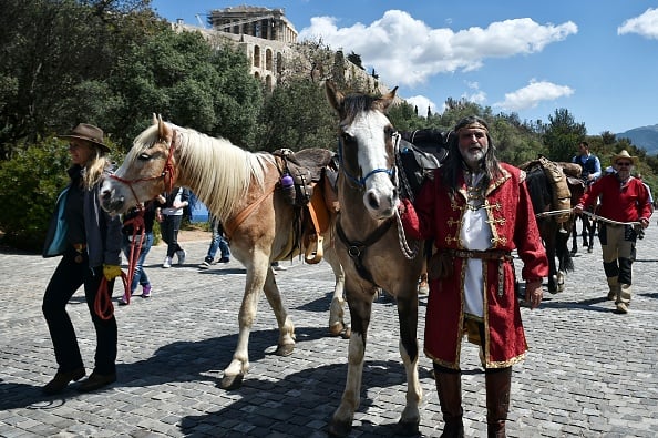 Riders walk with their horses beneath the Acropolis in Athens on April 9, 2017, marking the start of a 100-day horseback journey from Athens to Kassel, organized by artist Ross Birrell. Photo Louisa Gouliamaki/AFP/Getty Images.
