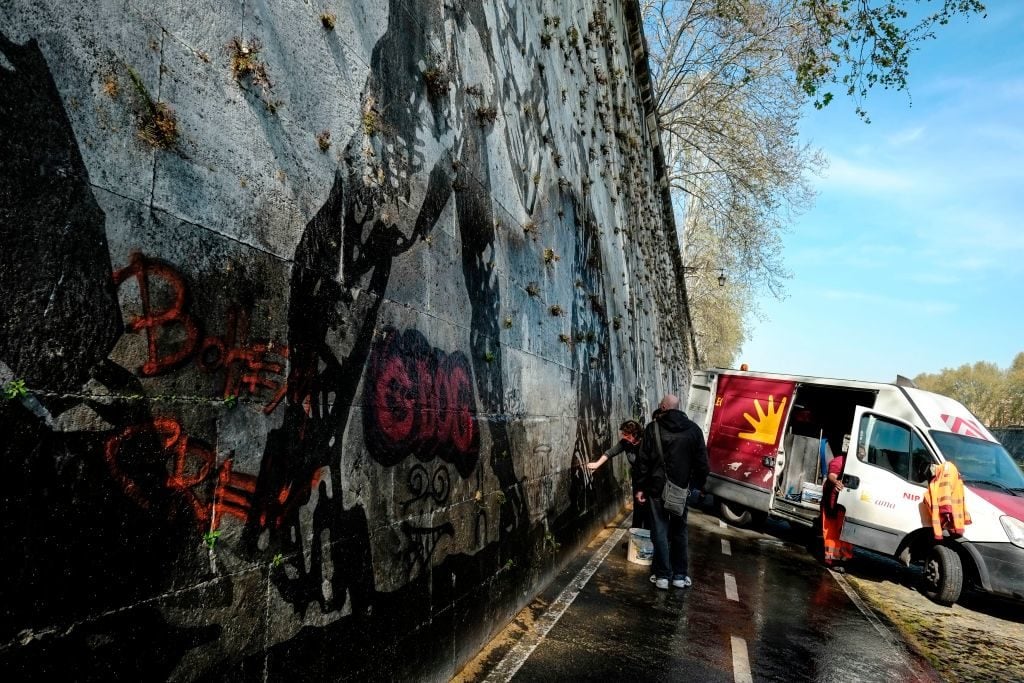 Workers try to remove graffiti on the Triumphs and Laments fresco which was completed along the banks of Rome’s Tiber river less than a year ago by South African artist William Kentridge, on March 31, 2017 in Rome. Photo ANDREAS SOLARO/AFP/Getty Images.