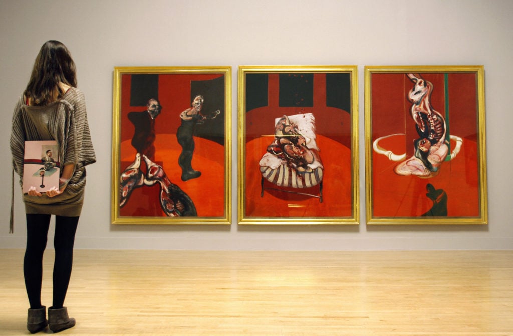 A visitor admires a triptych by Francis Bacon's Three Studies for a Crucifixion (1962) at the Tate Britain gallery in London on September 9, 2008. Image courtesy Adrian Dennis/AFP/Getty Images.