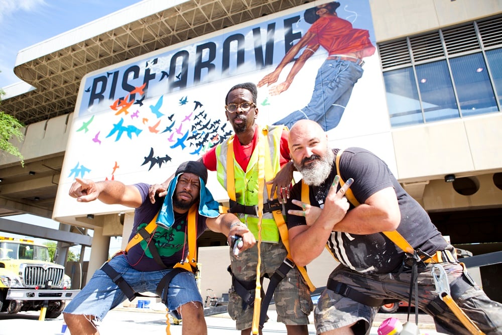 Fahamu Pecou (center) and his supporting artists Fabian Williams (left) and Joe Dreher (right) in front of the En Route mural on the King Memorial MARTA Station. Courtesy WonderRoot.