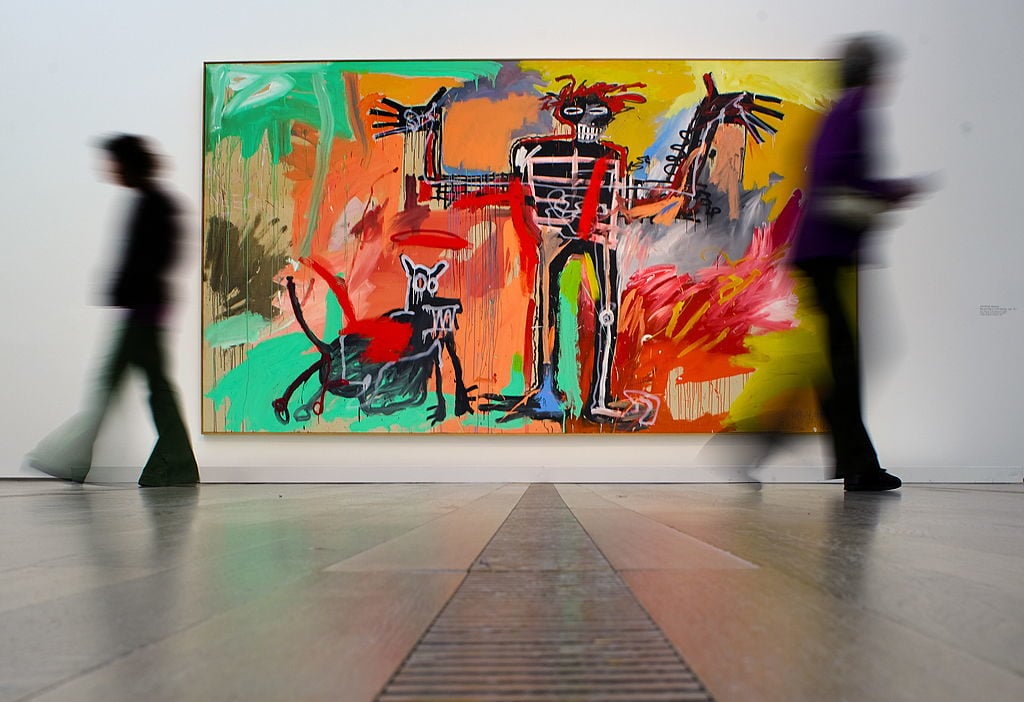 Visitors pass in front of a painting by Jean-Michel Basquiat entitled <em>Boy and Dog in a Johnnypump</em> on May 7, 2010, at Art Basel. Photo: Fabrice Coffrini/AFP/Getty Images.