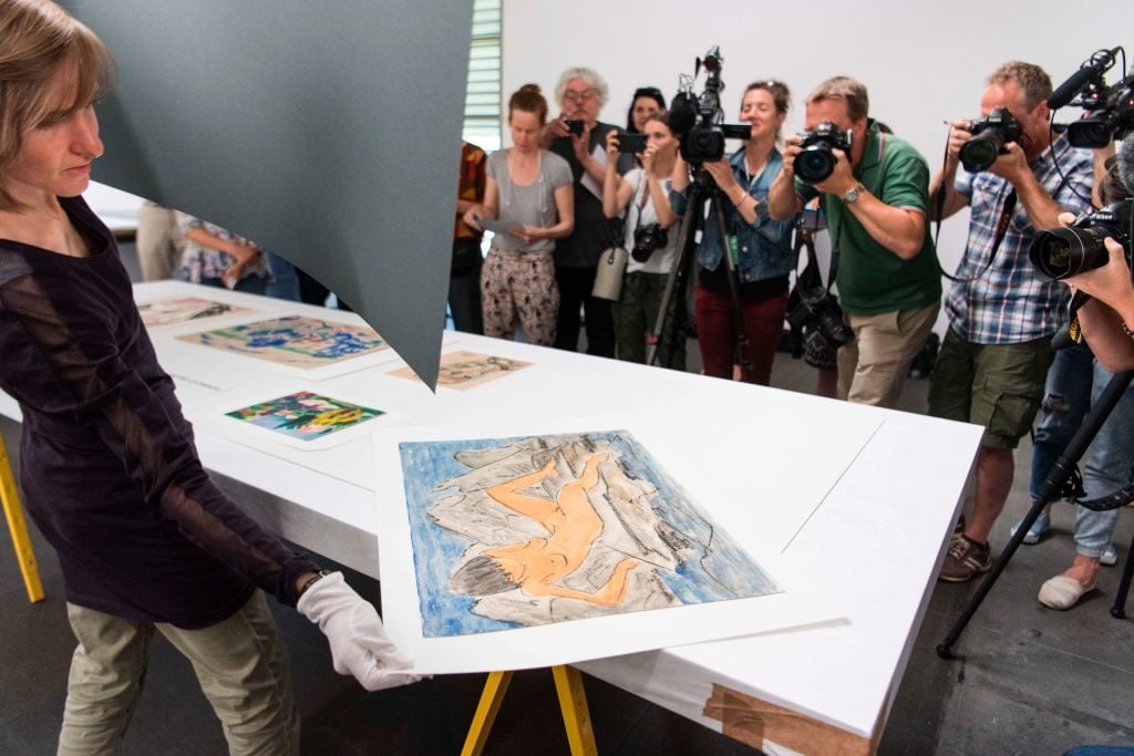 An official dsiplays the "Otto Mueller Liegende weiblicher Akt am Wasser, OJ Aquarell Kunstmuseum Bern, Legat Cornelius Gurlitt 2014" during a press preview of the first masterpieces of the estate of Cornelius Gurlitt at the Kunstmuseum Bern on July 7, 2017 in Bern. Photo: Valeriano di Domenico /AFP/Getty Images.