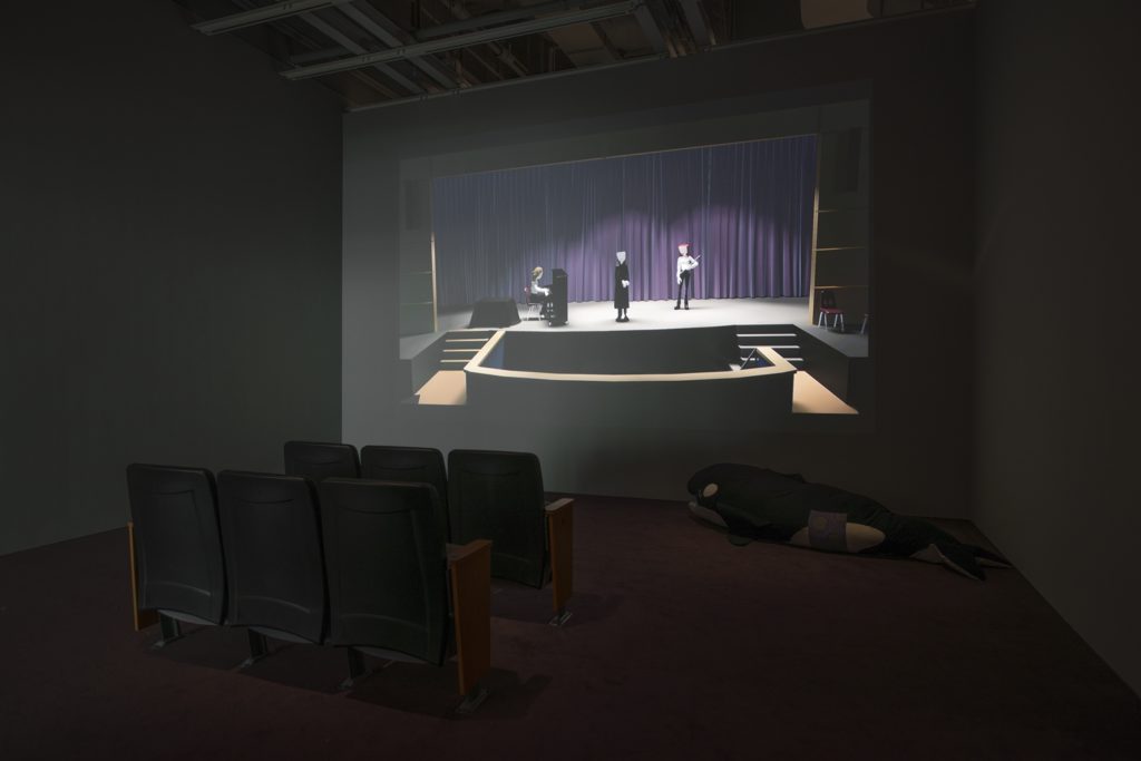 Installation view of Bunny Rogers: Brig Und Ladder (Whitney Museum of American Art, New York, July 7–October 9, 2017). From left to right: Columbine Auditorium seating, (2017); A Very Special Holiday Performance in Columbine Auditiorium (2017); Tilikum body pillow (2017). Photograph by Bill Orcutt.