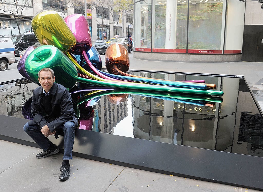 Jeff Koons poses with his sculpture 