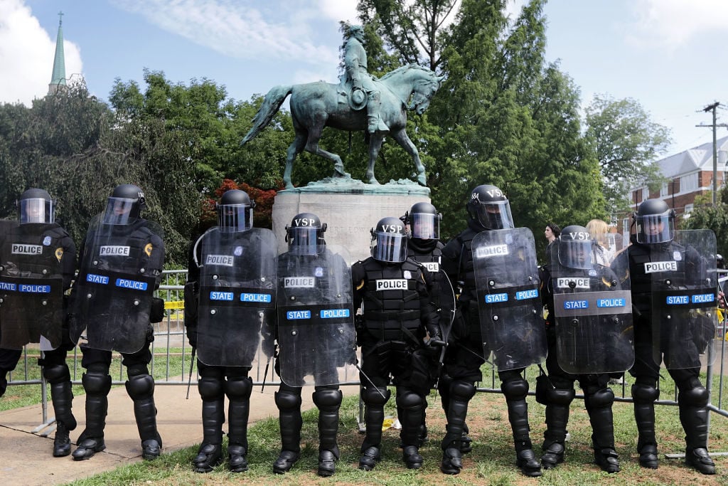 Virginia State Police in riot gear stand in front of the statue of General Robert E. Lee before forcing white nationalists, neo-Nazis and members of the 