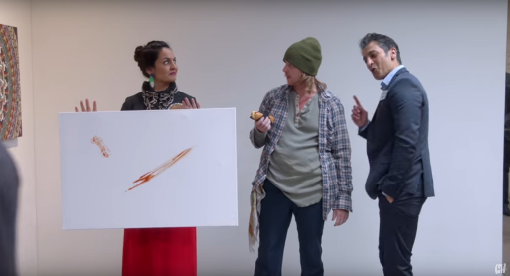 Two art dealers conspire to get rich off a hot dog-eating artist's "condiment-based" work. Photo via YouTube.