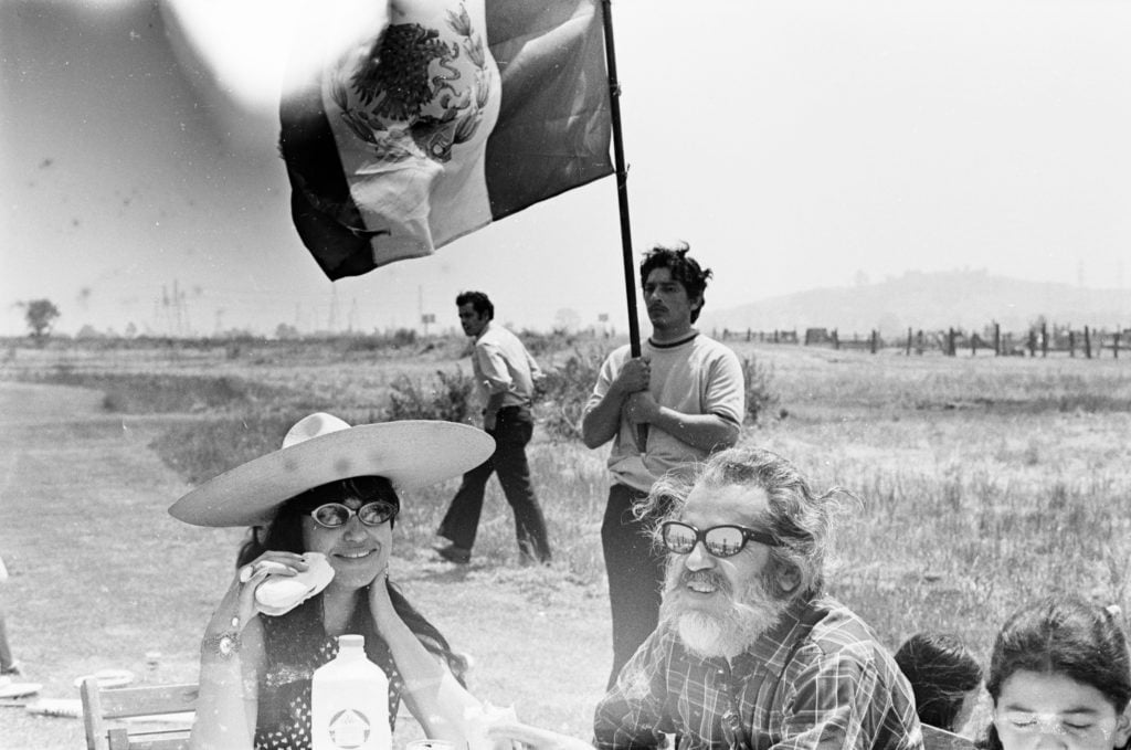A picnic in the fields during La Marcha de La Reconquista, Mike Heralda (wearing sunglasses), sits at picnic table. Circa 1971. Pedro Arias. Courtesy of the photographer and the UCLA Chicano Studies Research Center © Pedro Arias.