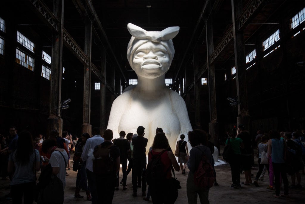 People view Kara Walker's "A Subtlety," a seventy-five-and-a-half-foot-long and thirty-five-and-a-half foot-tall sphinx made in part of bleached sugar at the former Domino Sugar Refinery on May 10, 2014, in Williamsburg. (Photo by Andrew Burton/Getty Images)