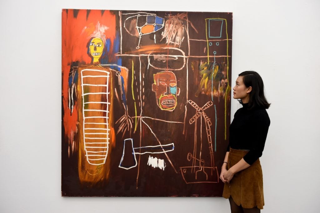 A gallery assistant gazes upon Jean-Michel Basquiat's Air Power at Sotheby's London. (Photo by Kate Green/Anadolu Agency/Getty Images)
