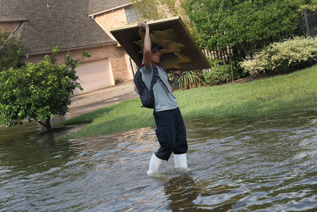 Tito Rodriguez carries a painting as he volunteers his time to help bring items out of homes inundated with flood water in an area where a mandatory evacuation is still under effect after torrential rains caused widespread flooding during Hurricane and Tropical Storm Harvey on September 3, 2017 in Houston, Texas. Photo by Joe Raedle/Getty Images.