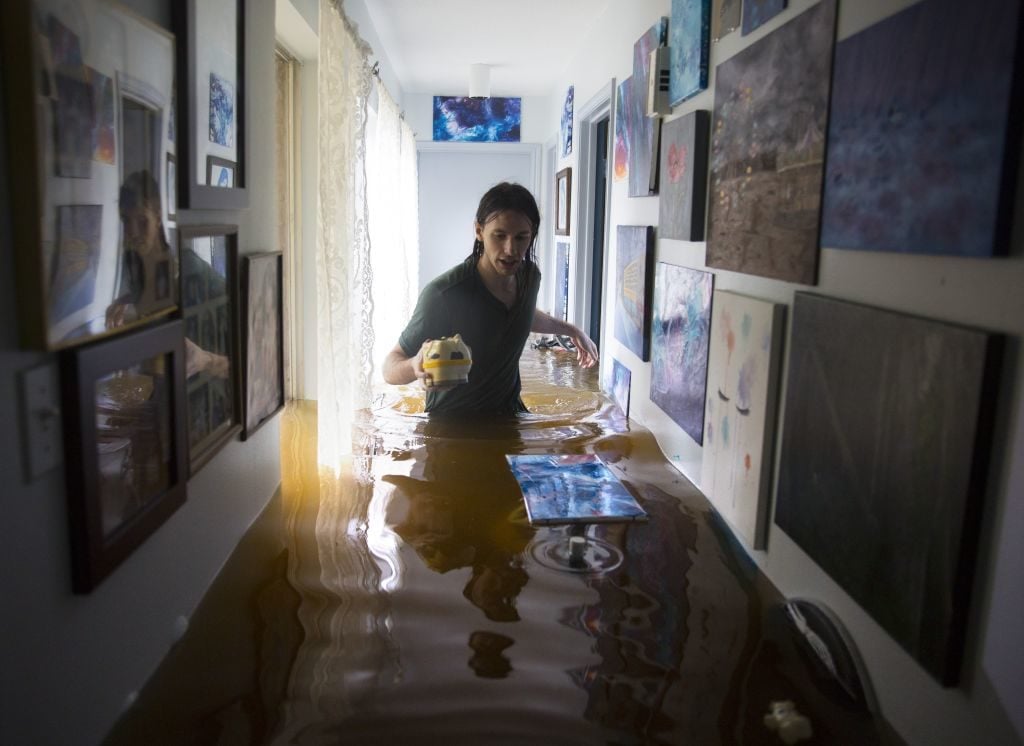 Matthew Koser looks for important papers and heirlooms inside his grandfather's house after it was flooded by heavy rains from Hurricane Harvey August 29, 2017 in the Bear Creek neighborhood of west Houston, Texas. Photo by Erich Schlegel/Getty Images.